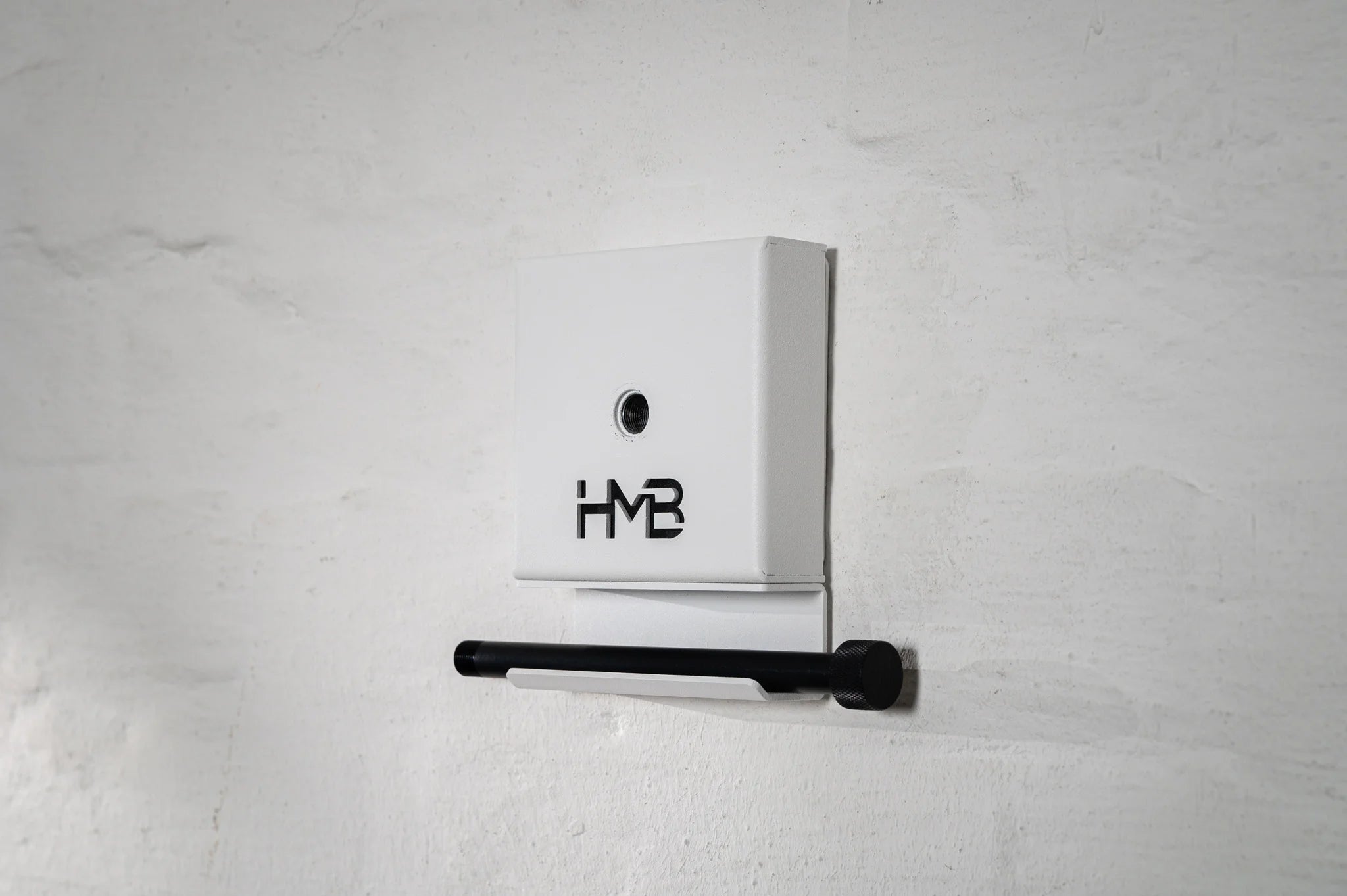 Perspective side view of the white Hold My Bike (HMB) wheel mount: The minimalist design combines a sturdy wheel hanger with a practical shelf to store the 12mm thru-axle.