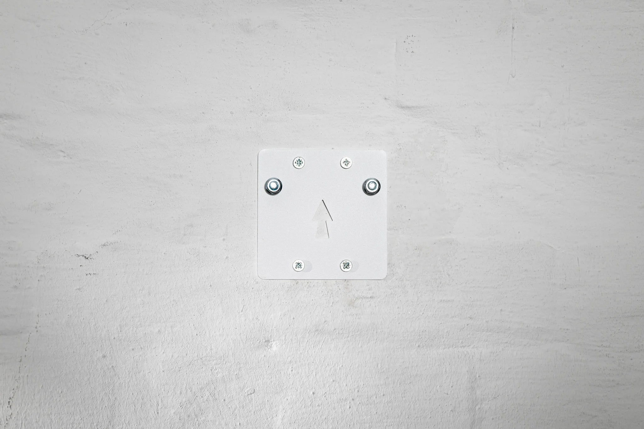 The white mounting plate of the Hold My Bike (HMB) wheel mount features the HMB Easy Mounting System with an integrated arrow for precise vertical wall alignment.