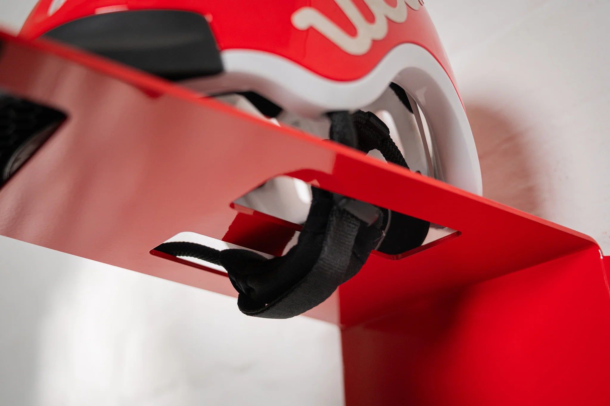 Close-up view of a red woom helmet resting on the top shelf of an HMB Kids mount, showing the secure fit and easy-access design.