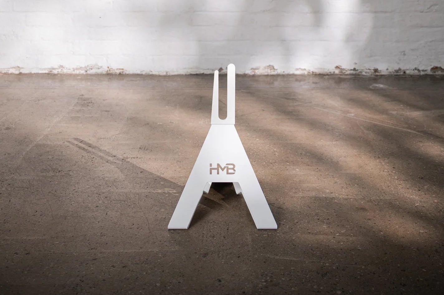 Front view of the white Hold My Bike (HMB) bike stand: The minimalist A-frame design made of powder-coated metal provides a stable, freestanding indoor bike storage solution.
