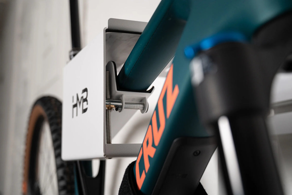 Close-up of a Santa Cruz mountain bike secured in the white HMB Ultimate XL wall mount, highlighting the innovative tilt mechanism and threaded adjustment rod used to level the bike's frame.