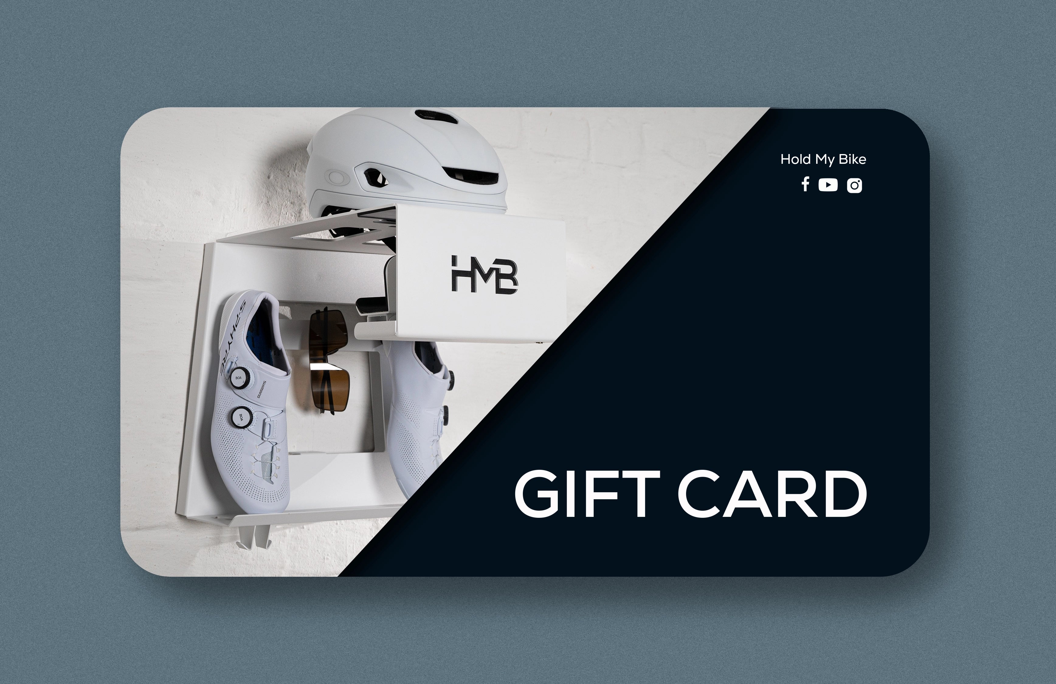 Hold My Bike (HMB) gift card for cyclists: White indoor bike wall mount featuring a helmet, cycling shoes, and sunglasses in an apartment setting.