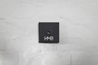 The elegant black Hold My Bike (HMB) wheel mount featuring subtle logo branding for aesthetic indoor bike wheel storage in your apartment.