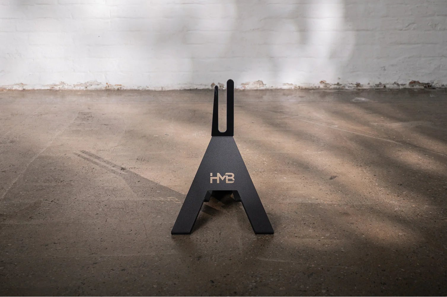 Front view of the black Hold My Bike (HMB) bike stand: The minimalist A-frame design made of powder-coated metal provides a stable, freestanding indoor bike storage solution.