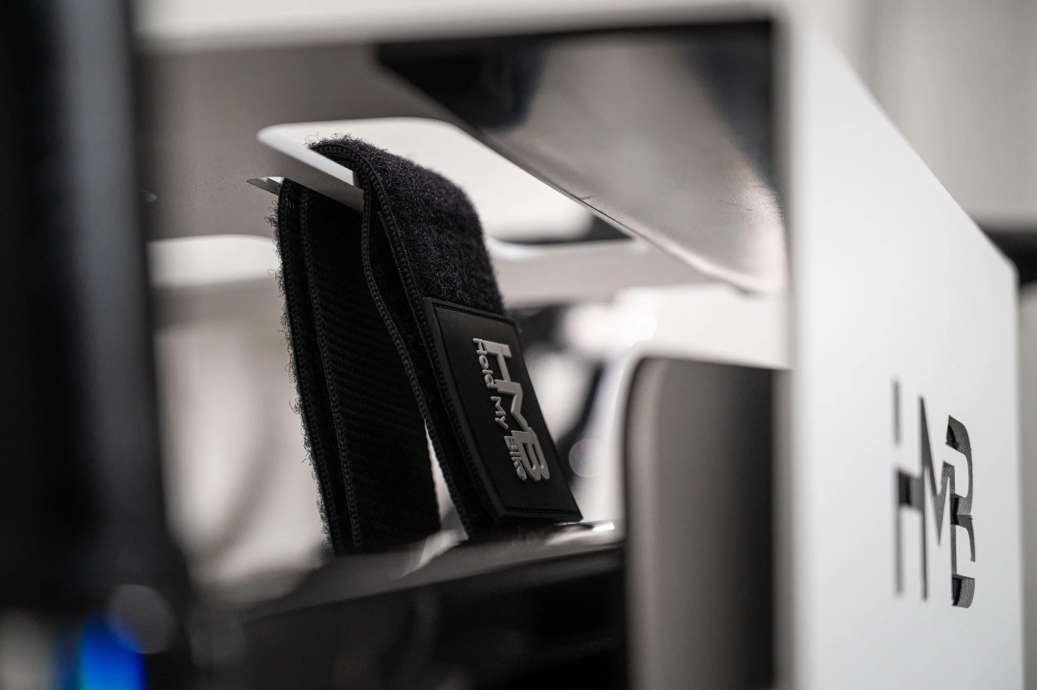 Close-up of the black Hold My Bike (HMB) Wheel Strap, featuring a special cutout design in the wall mount to securely lock the bike in place and prevent it from falling.
